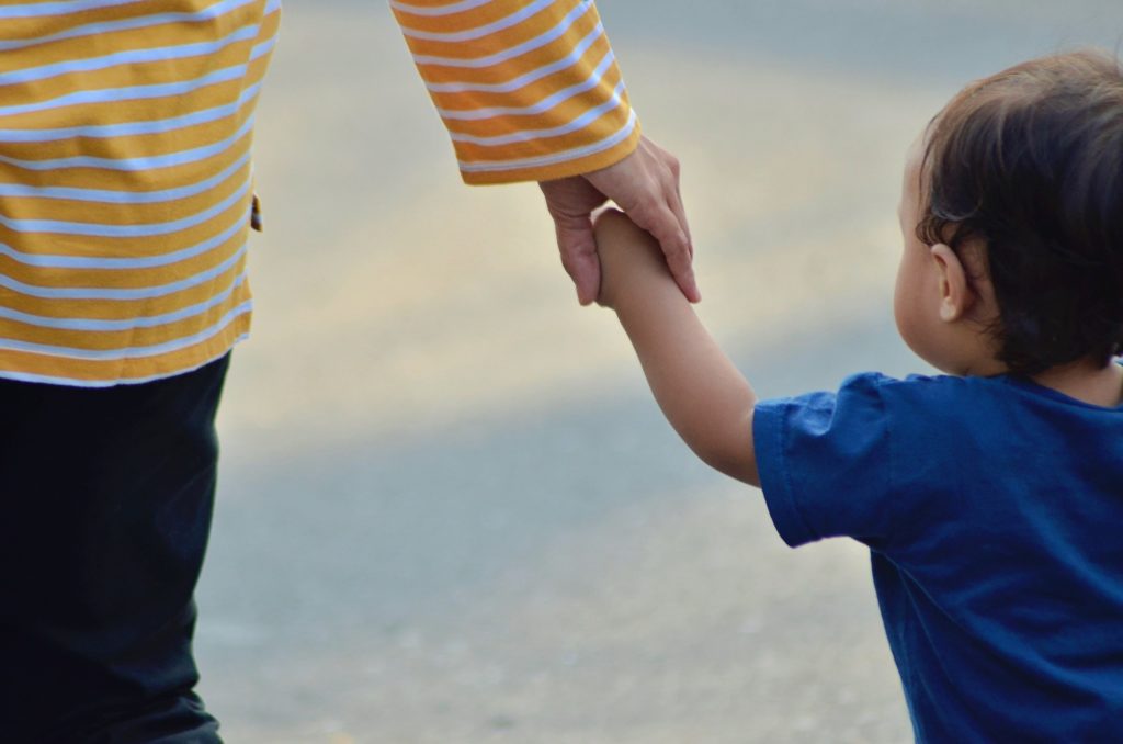 image of an adult holding a toddlers hand