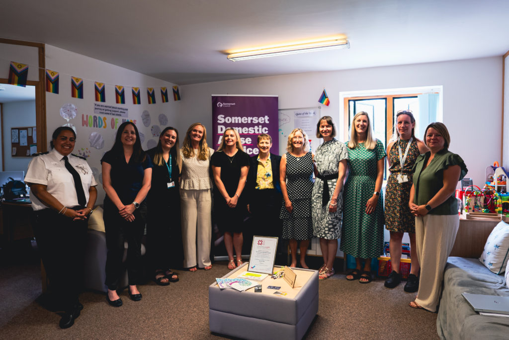 Group of people stood in a row in an office.