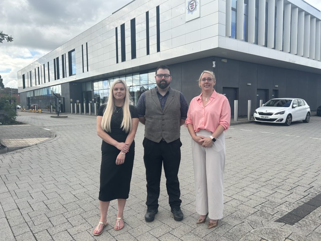 Three people stood outside building.